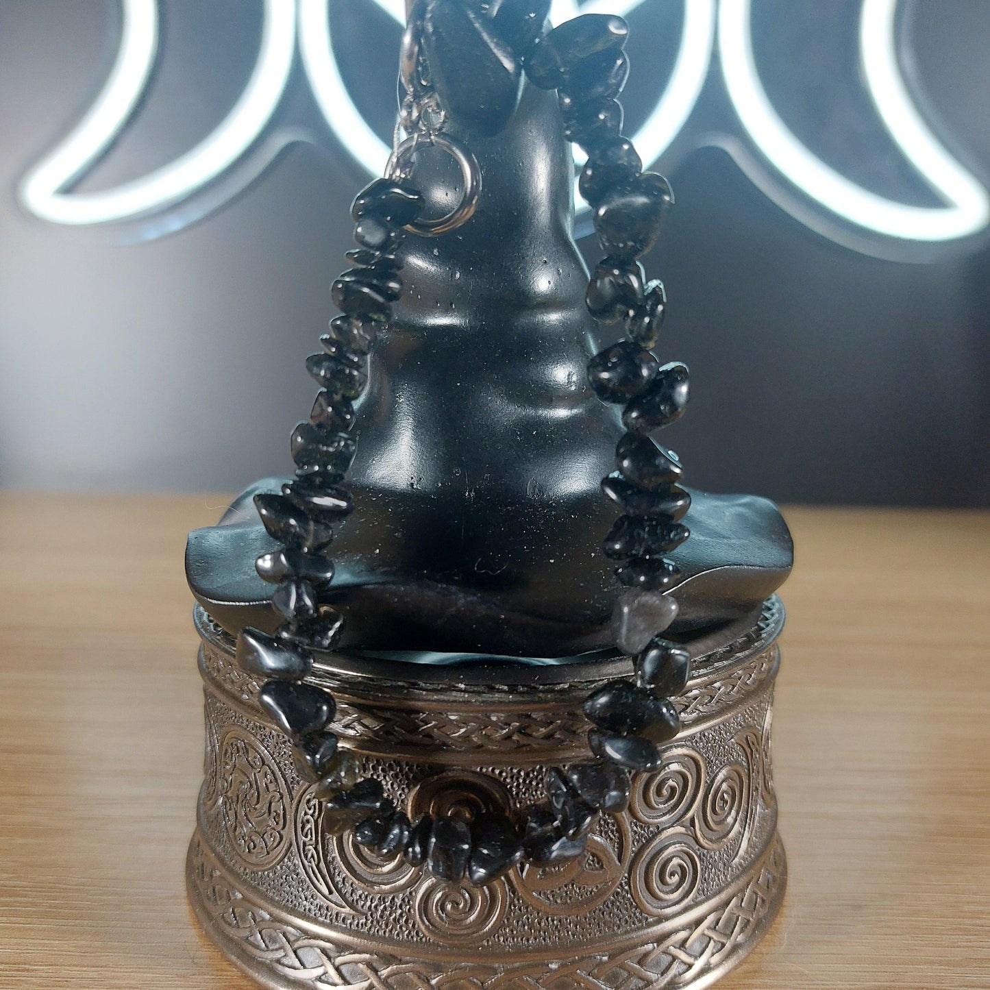 Black obsidian crystal chip bracelet with stainless steel toggle clasp on a dark witch hat display.