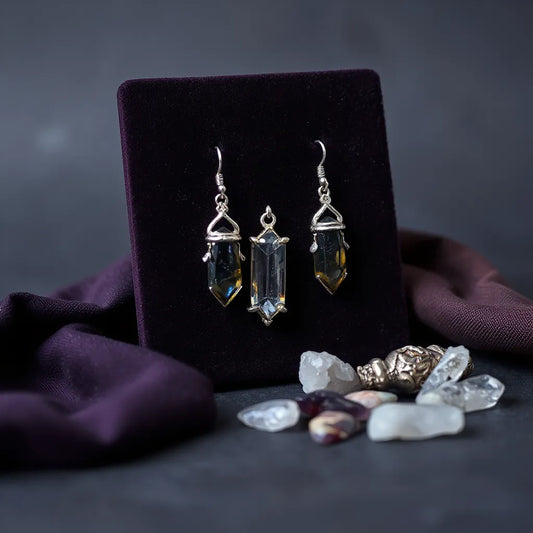 Pair of witch-inspired crystal drop earrings on dark velvet with small crystals nearby
