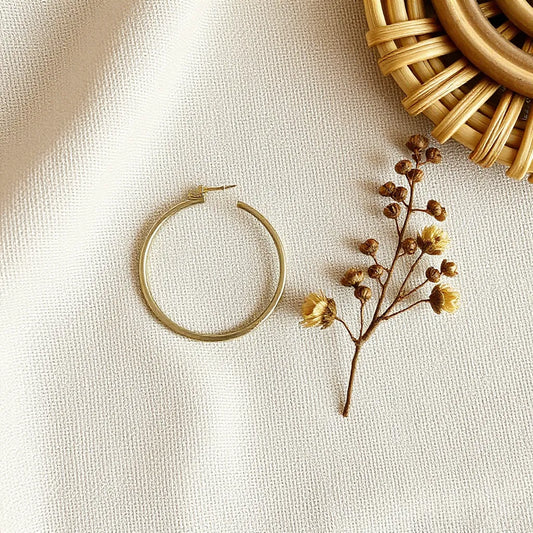Bohemian hoop earrings with subtle bead and charm details on a neutral fabric backdrop.