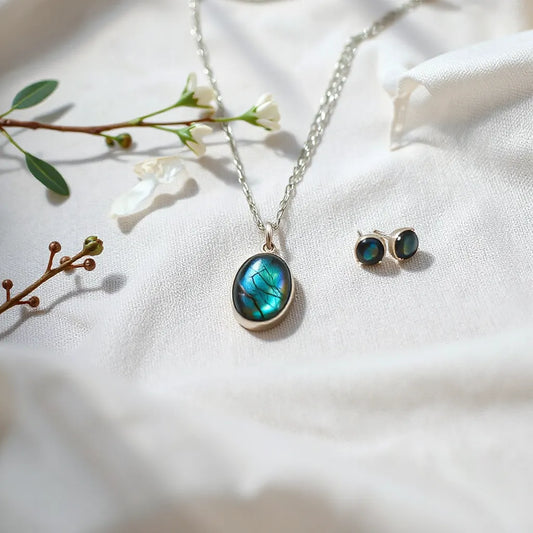 Handcrafted labradorite pendant necklace and earrings on neutral linen with iridescent gemstone glow