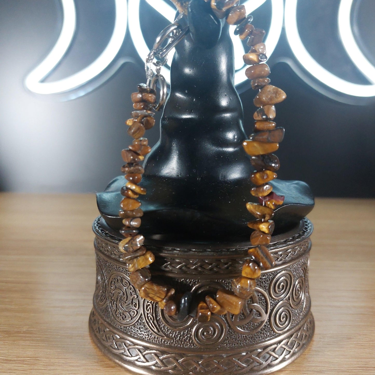 Tigers Eye crystal chip bracelet with stainless steel toggle clasp, displayed on a decorative stand.
