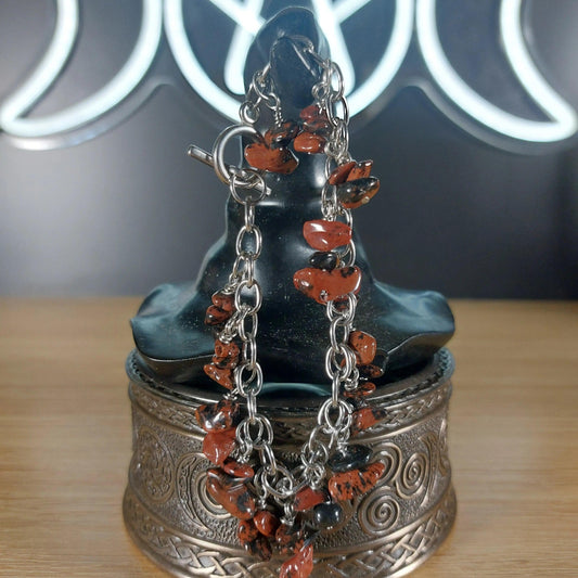 Mahogany obsidian chip bracelet with stainless steel chain on a dark display bust.