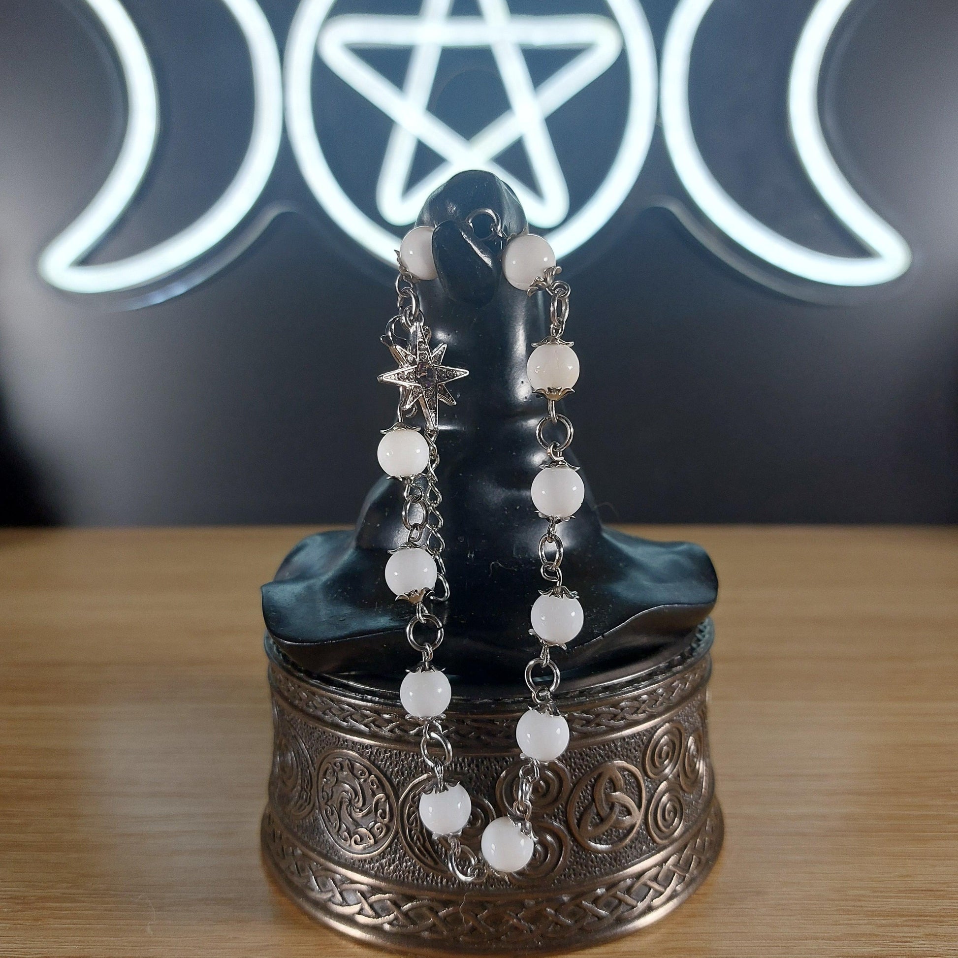 White shell beaded bracelet with silver-tone chain, bead caps, and a starburst charm.