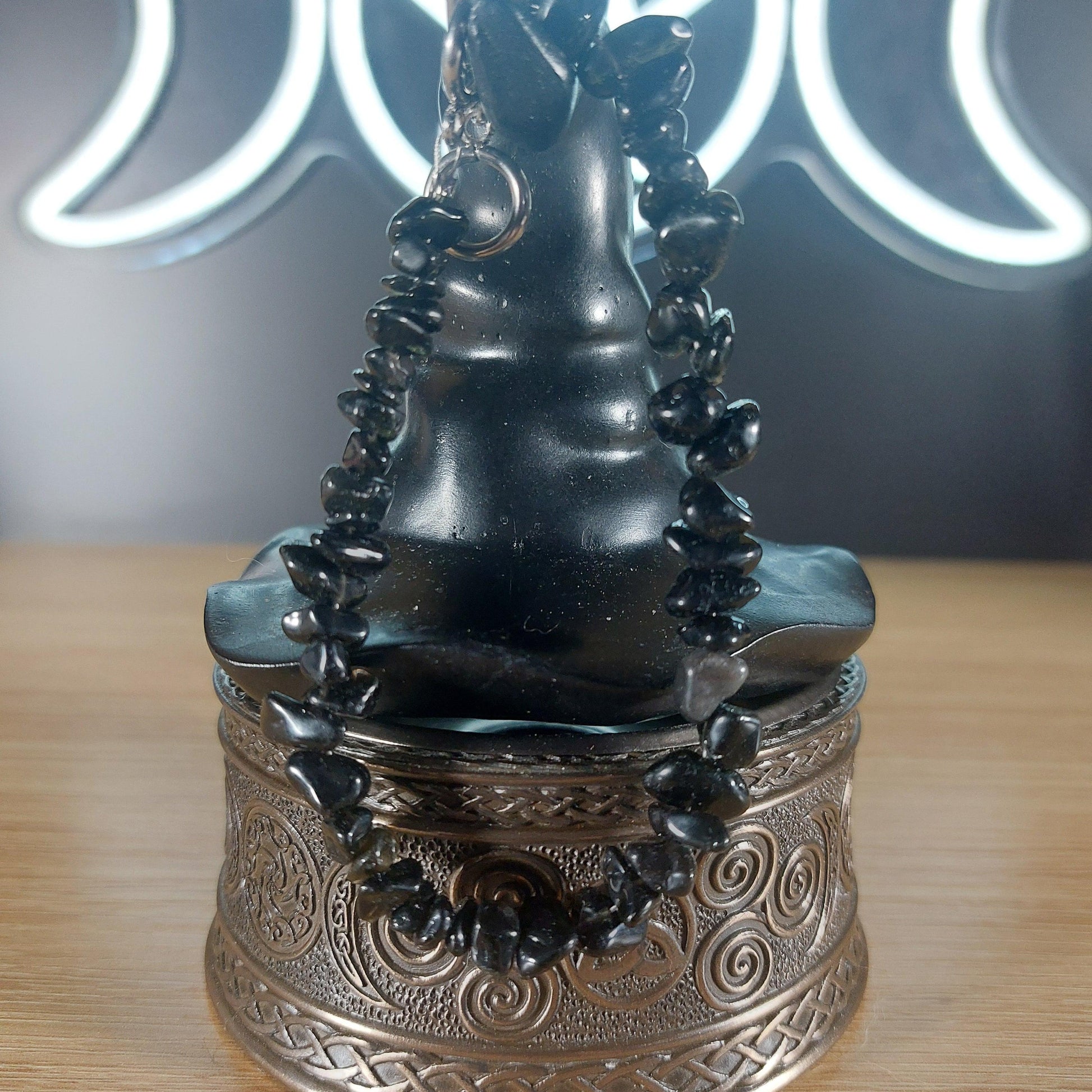 Black obsidian crystal chip bracelet with stainless steel toggle clasp on a dark witch hat display.