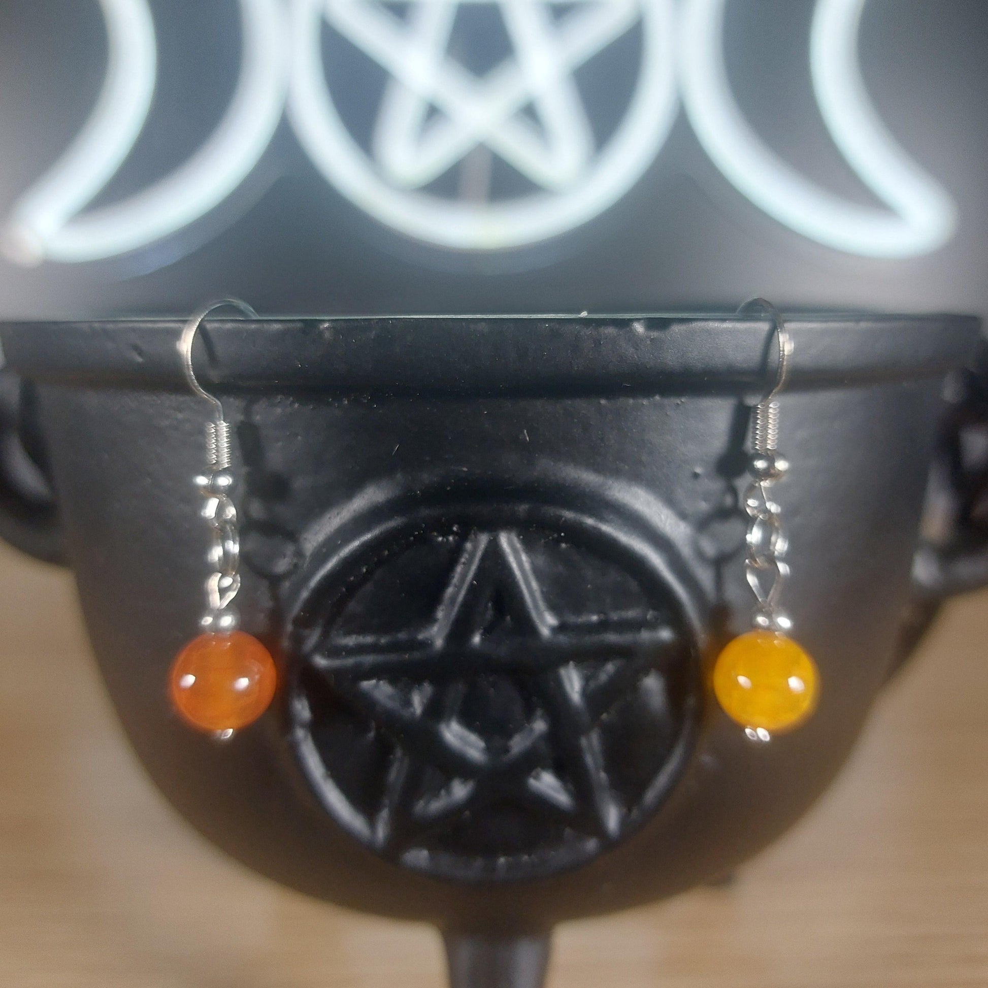 Yellow chalcedony crystal beaded dangle earrings with silver hooks, displayed on a black cauldron.